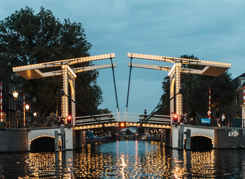 Beautiful Magere Brug over the canal in Amsterdam, reflecting lights at dusk.