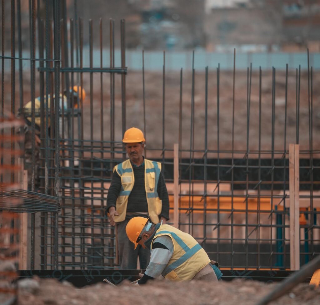 Construction workers on site adding steel reinforcement bars. Urban environment, teamwork in progress.